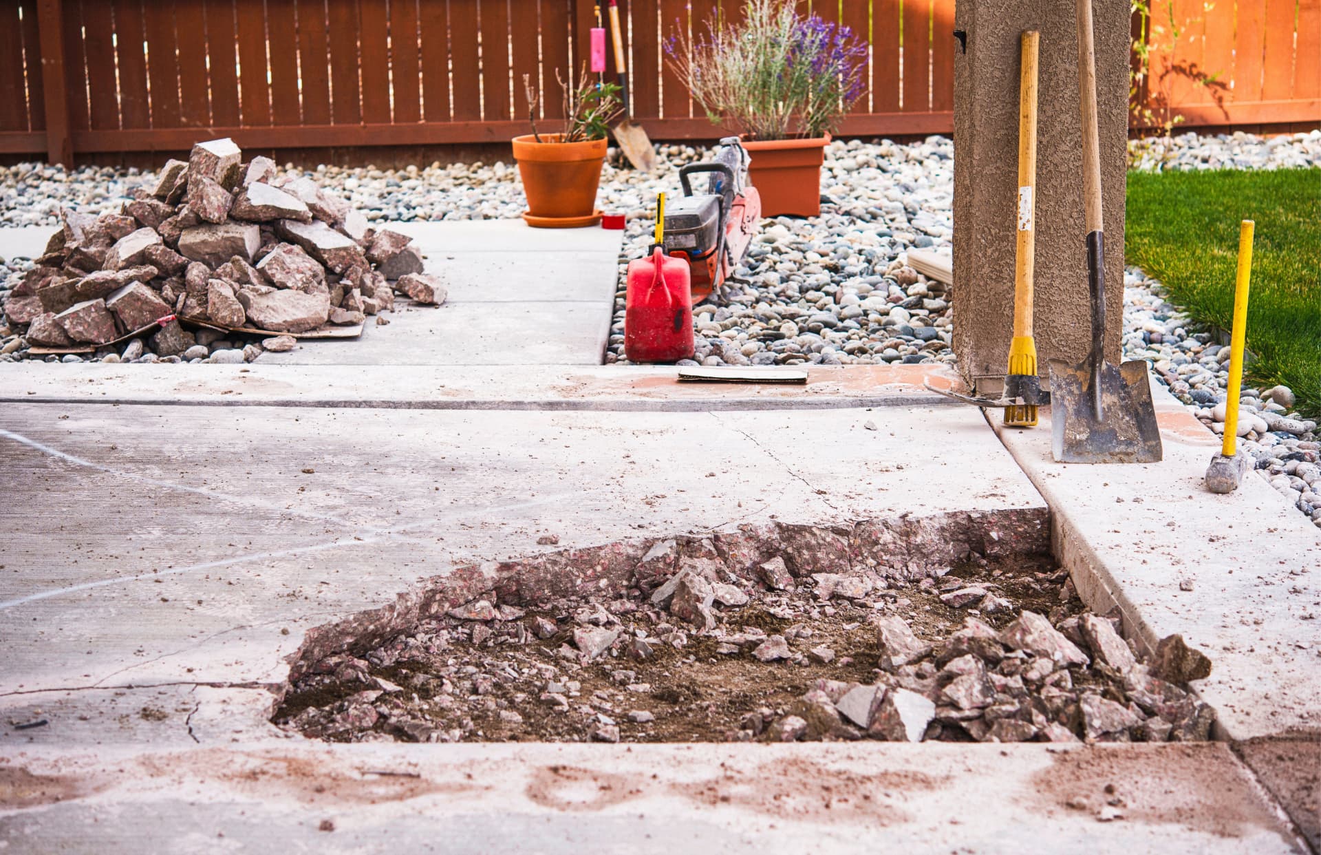 Broken concrete slab cut out of a patio with rubble piled beside it
